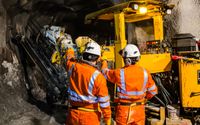 Operarios de naranja revisando una excavadora en una mina